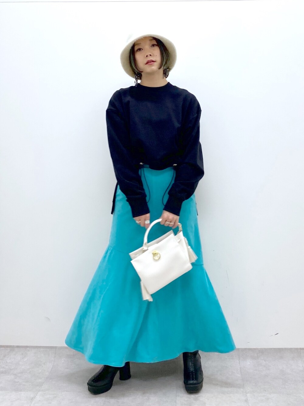 ホワイト系のショルダーバッグ、ブラック系のブーツ、ブラック系のトップスを着用したレディースの冬コーディネートの5枚目の写真