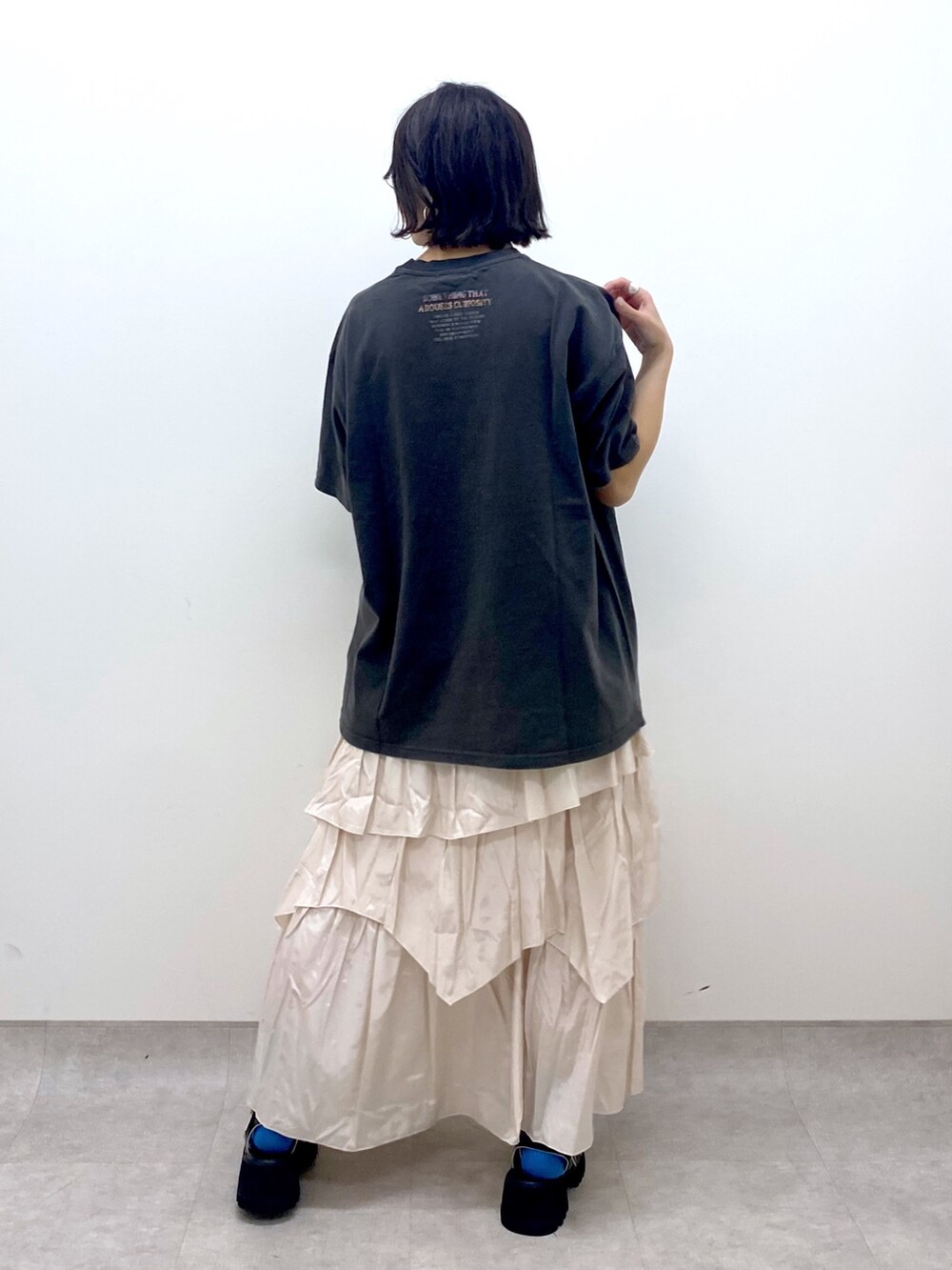 グレー系のTシャツ/カットソー、ホワイト系のスカート、ブラック系のサンダルを着用したレディースの春コーディネートの3枚目の写真