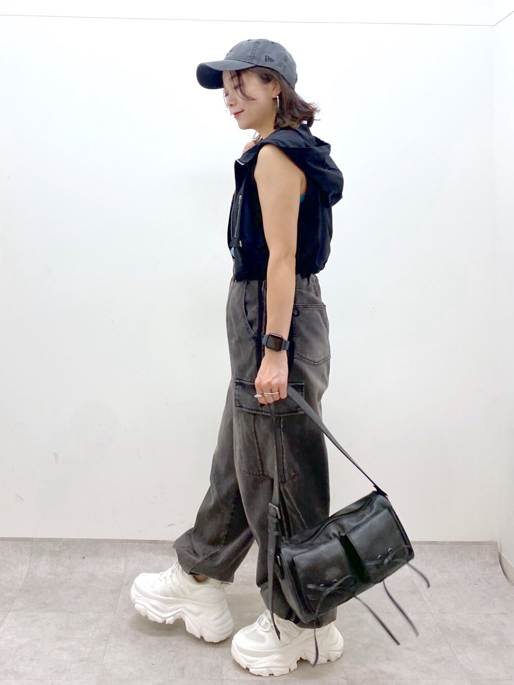 ブラウン系のデニムパンツ、ブラック系のショルダーバッグ、ホワイト系のスニーカーを着用したレディースの夏コーディネートの5枚目の写真