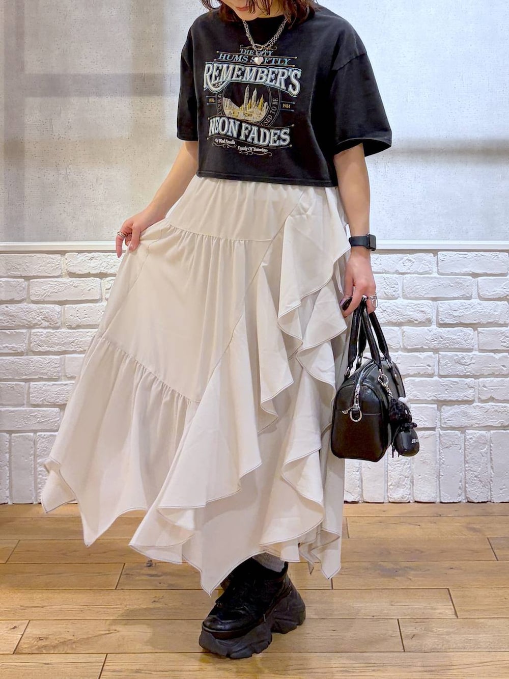 ブラック系のスニーカー、ベージュ系のスカート、ブラック系のボストンバッグを着用したレディースの春コーディネートの3枚目の写真