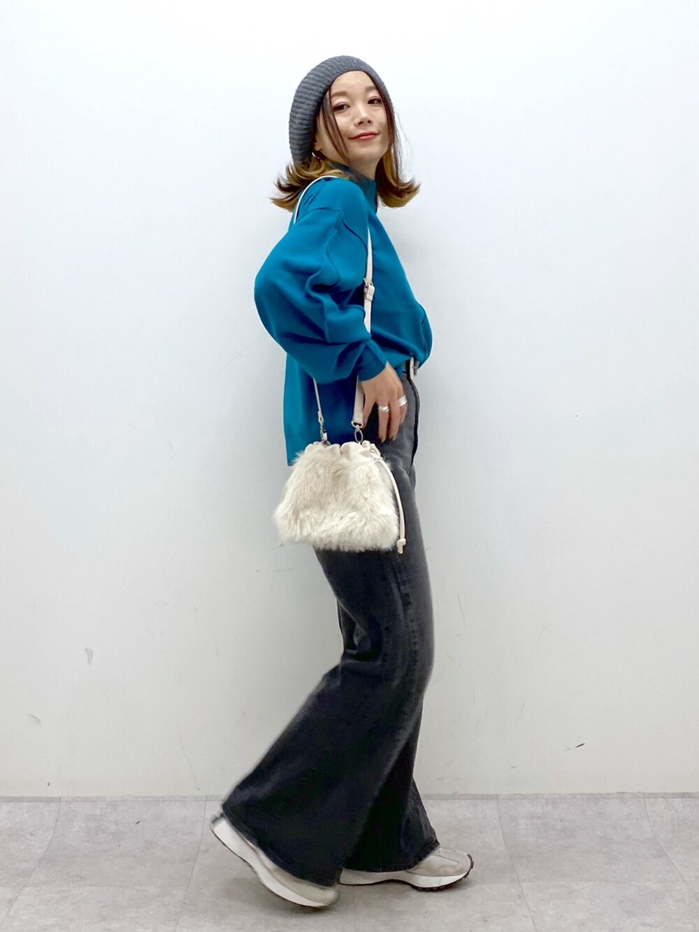 ブラック系のデニムパンツ、ホワイト系のショルダーバッグ、ブルー系のニット/セーターを着用したレディースの秋コーディネートの6枚目の写真