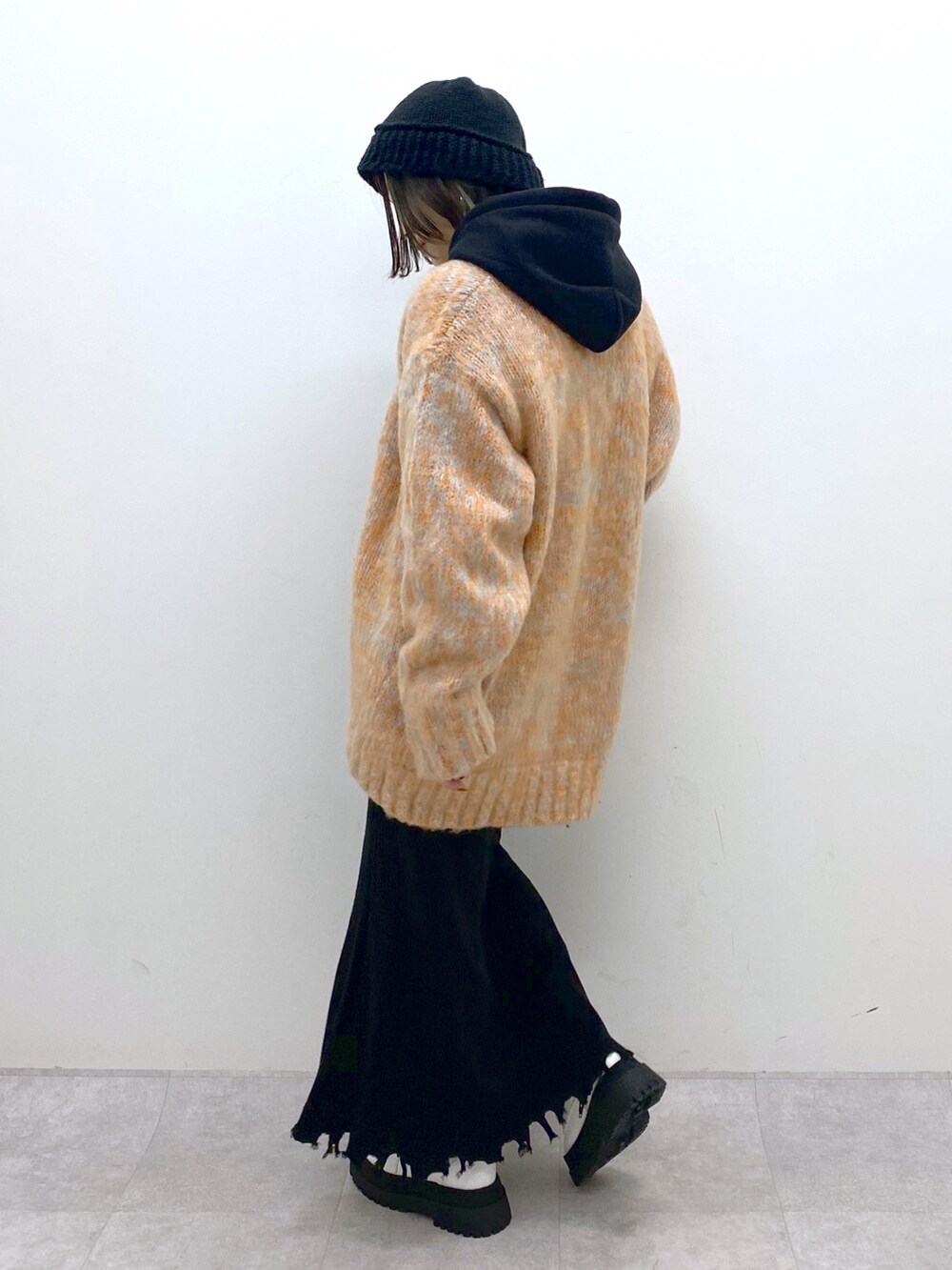 ブラック系のトップス、オレンジ系のカーディガン/ボレロ、ブラック系のスカートを着用したレディースの冬コーディネートの3枚目の写真