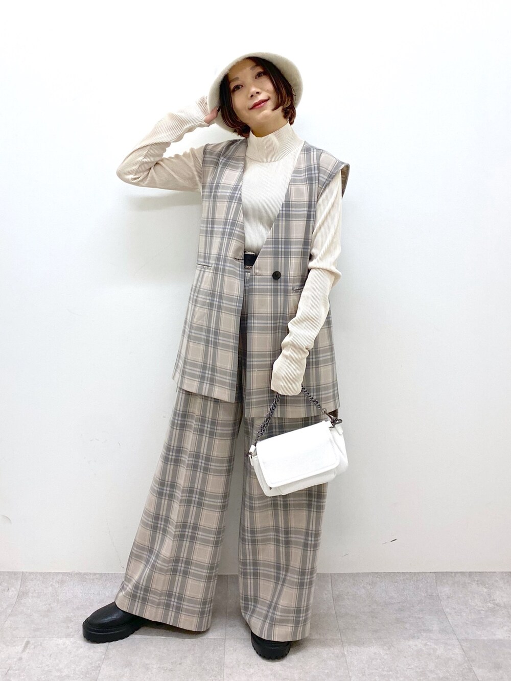 ホワイト系のバッグ、ブラック系のシューズ、グレー系のパンツを着用したレディースの秋コーディネートの2枚目の写真