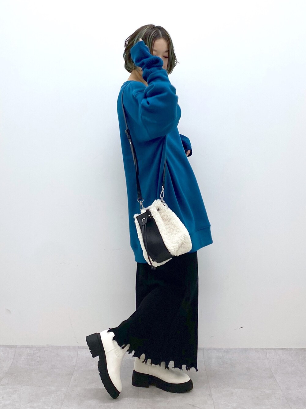 ホワイト系のバッグ、ホワイト系のシューズ、ブラック系のスカートを着用したレディースの冬コーディネートの2枚目の写真