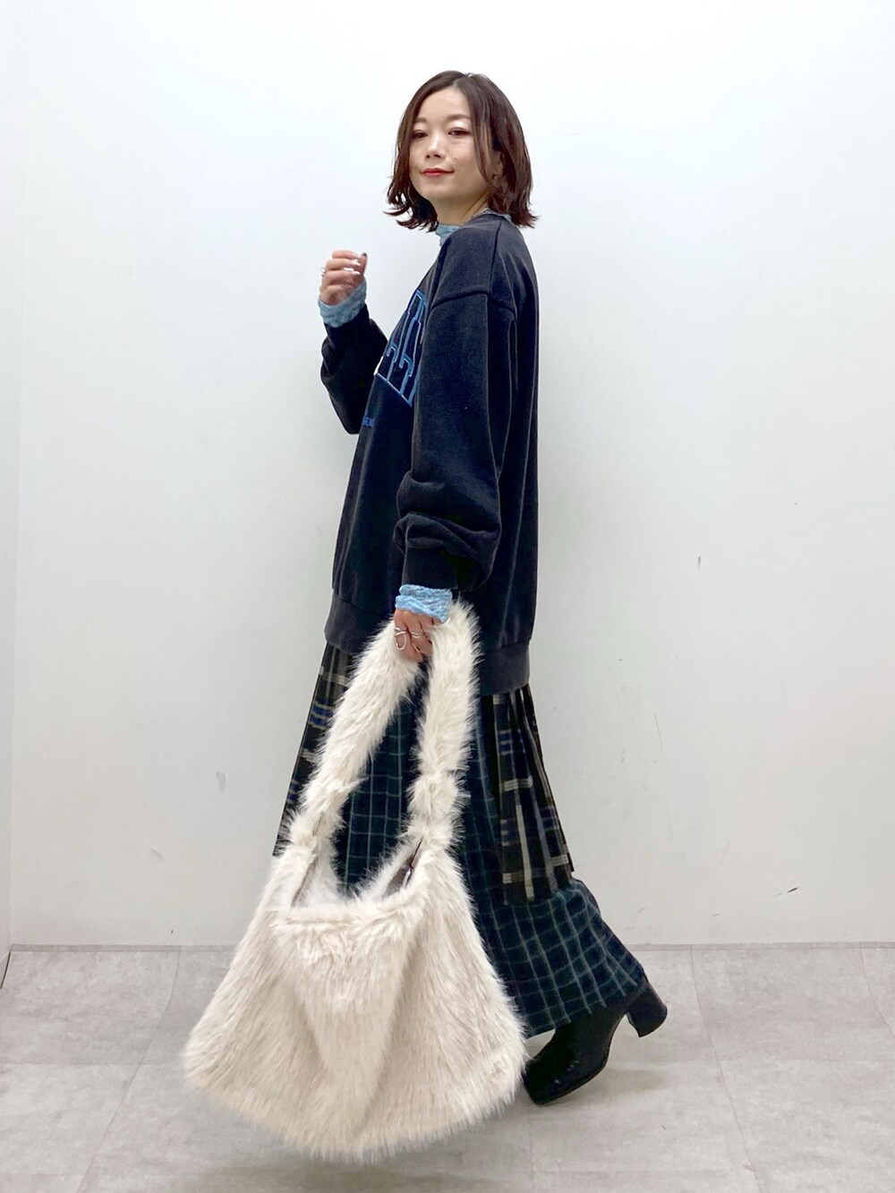 グレー系のスウェット、ブルー系のスカート、ホワイト系のショルダーバッグを着用したレディースの秋コーディネートの7枚目の写真