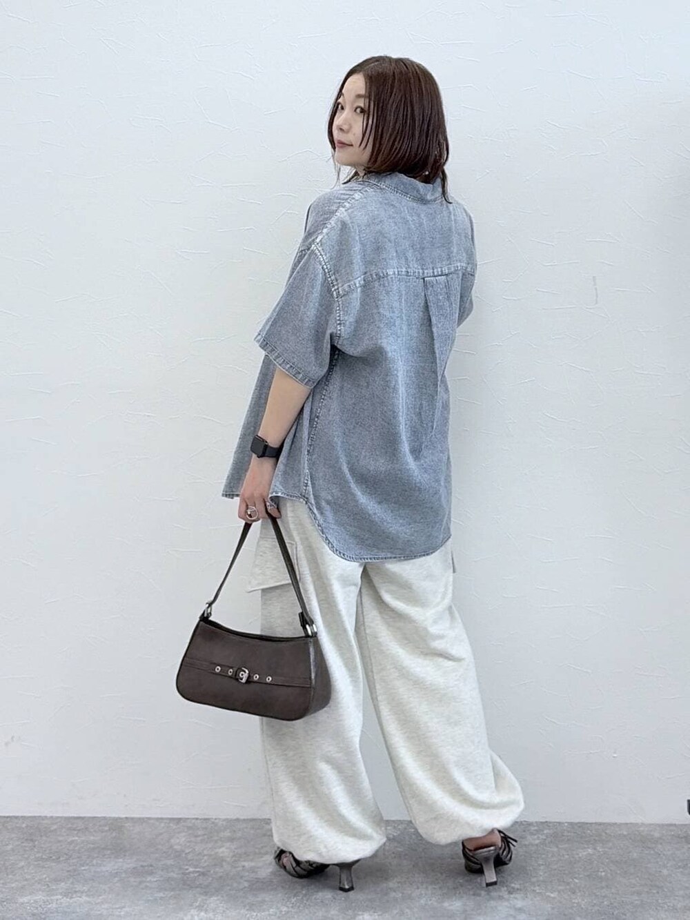 ブラウン系のハンドバッグ、ブルー系のシャツ/ブラウス、ブラック系のタンクトップを着用したレディースの春コーディネートの7枚目の写真
