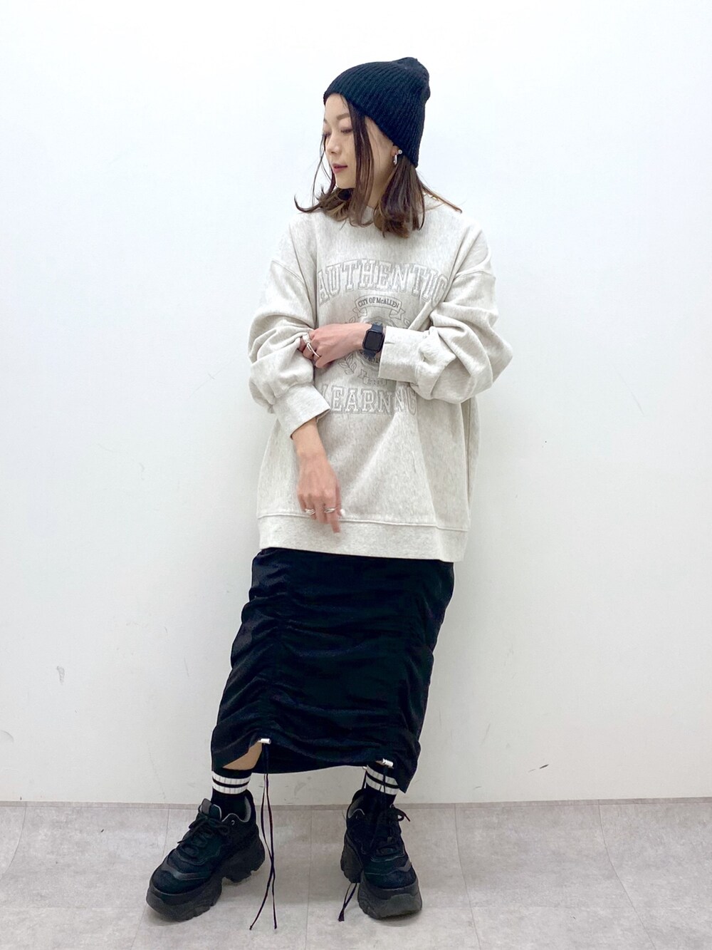 ベージュ系のスウェット、ブラック系のワンピース、ブラック系のスニーカーを着用したレディースの冬コーディネートの9枚目の写真