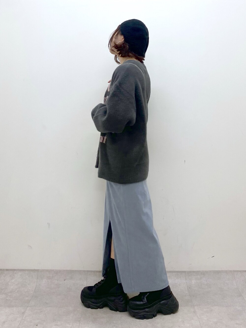 グレー系のニット/セーター、ブルー系のスカート、ブラック系のブーツを着用したレディースの秋コーディネートの5枚目の写真