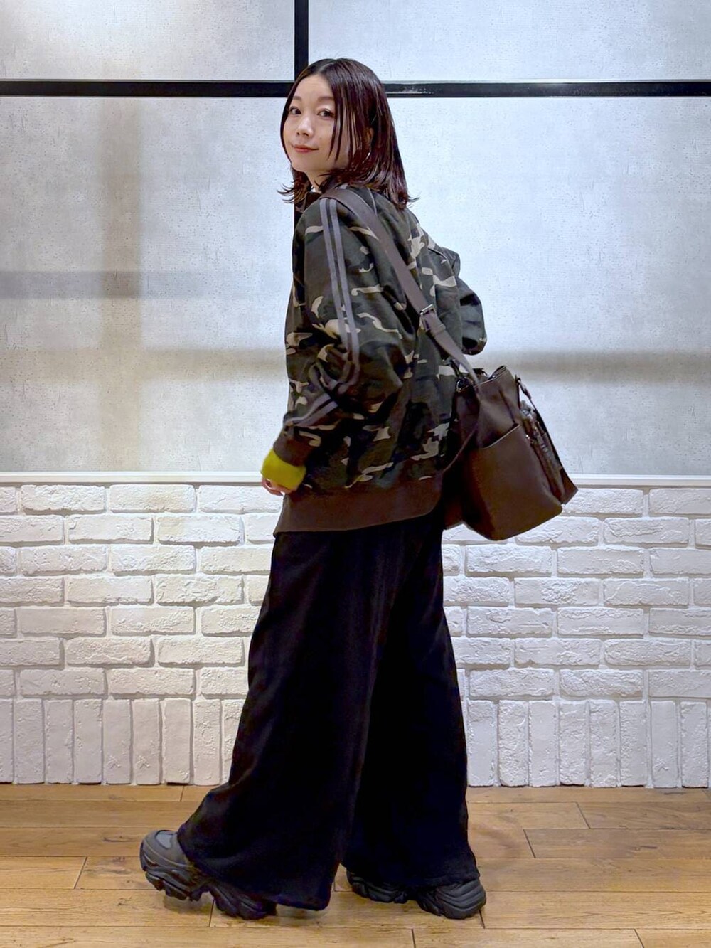 グレー系のスニーカー、ブラウン系のボストンバッグ、イエロー系のニット/セーターを着用したレディースの冬コーディネートの4枚目の写真