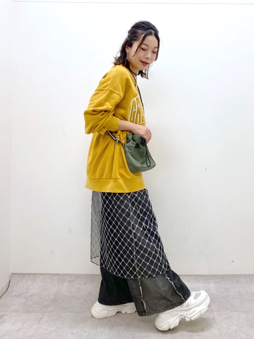 イエロー系のスウェット、ブラック系のデニムパンツ、ホワイト系のスニーカーを着用したレディースの夏コーディネートの7枚目の写真