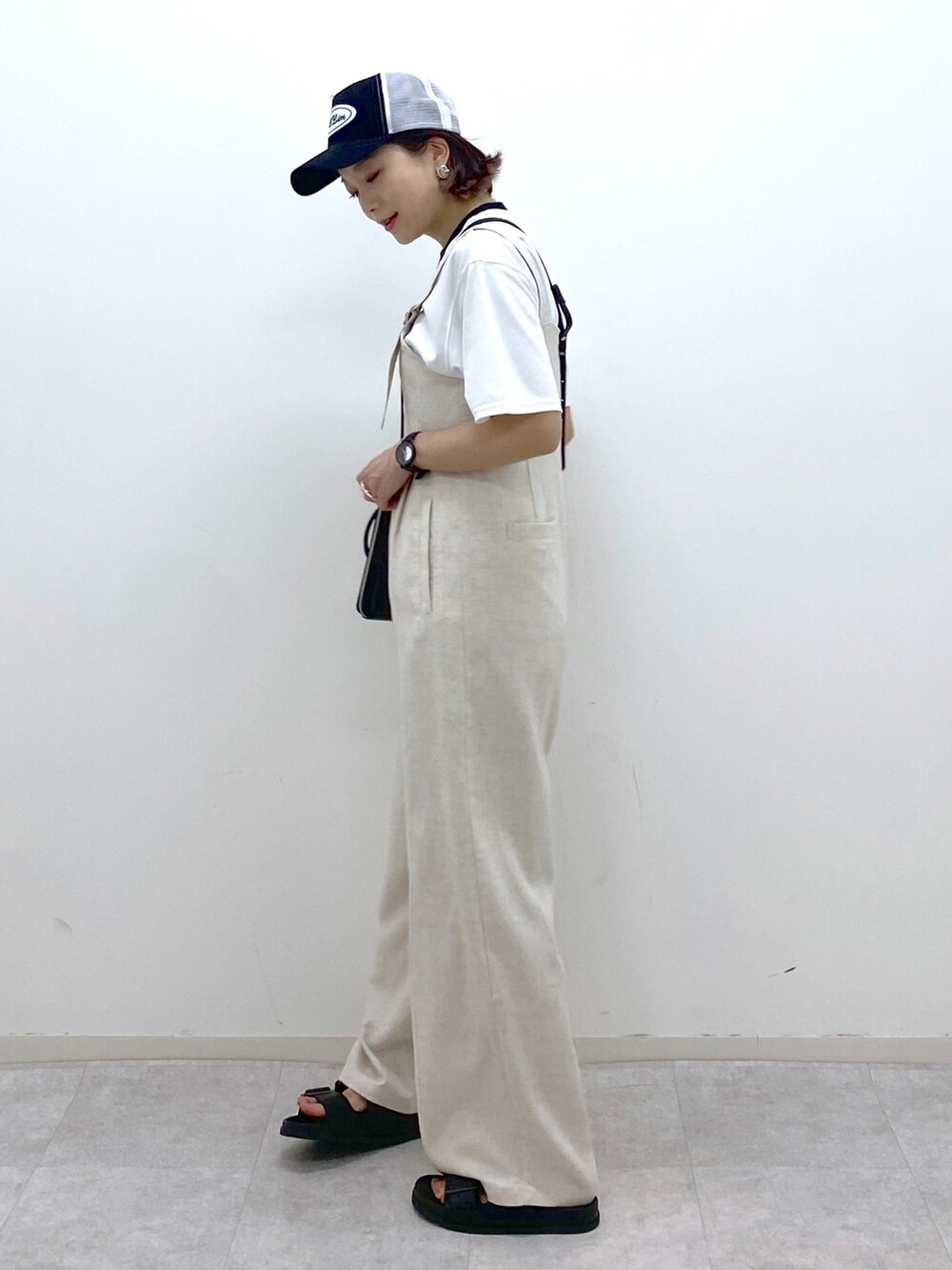 ホワイト系のサロペット/オーバーオール、ブラック系のサンダル、ホワイト系のTシャツ/カットソーを着用したレディースの夏コーディネートの4枚目の写真