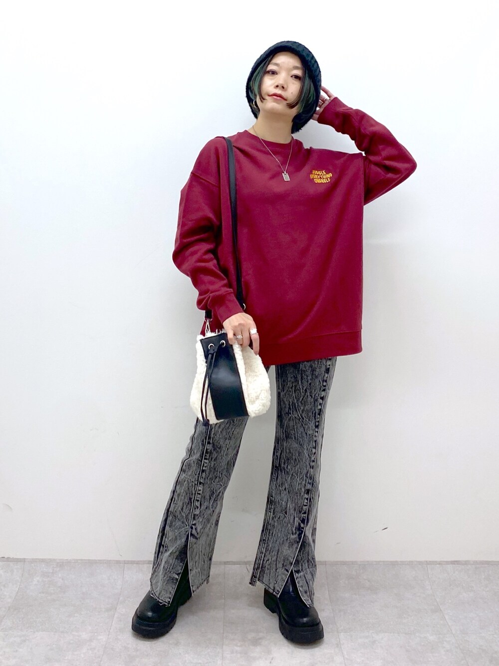 レッド系のスウェット、ブラック系のデニムパンツ、ブラック系のシューズを着用したレディースの秋コーディネートの2枚目の写真