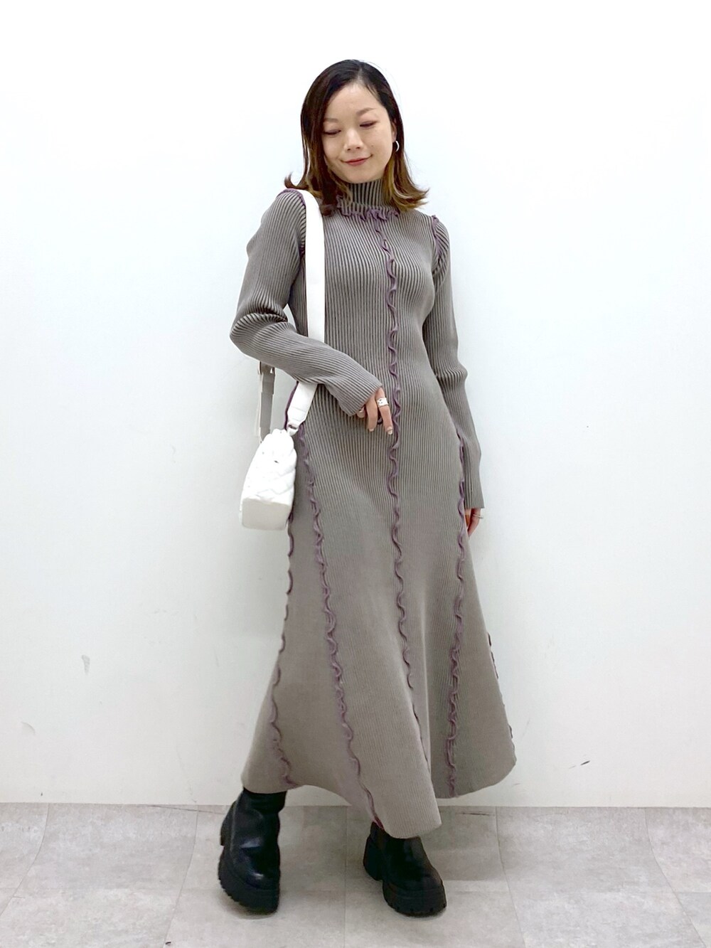 ブラウン系のワンピース、ホワイト系のショルダーバッグ、ブラック系のブーツを着用したレディースの秋コーディネートの2枚目の写真