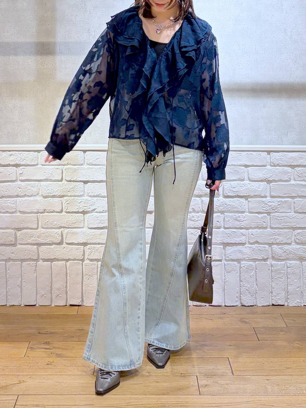 ブラック系のキャミソール、ブルー系のデニムパンツ、ブラウン系のハンドバッグを着用したレディースの春コーディネートの3枚目の写真