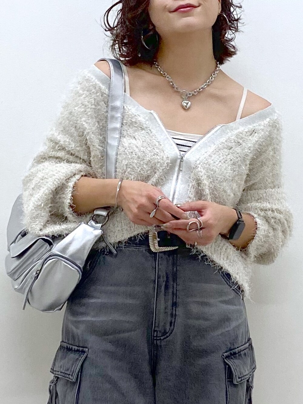 ブラック系のデニムパンツ、ブラック系のブーツ、シルバー系のショルダーバッグを着用したレディースの秋コーディネートの2枚目の写真