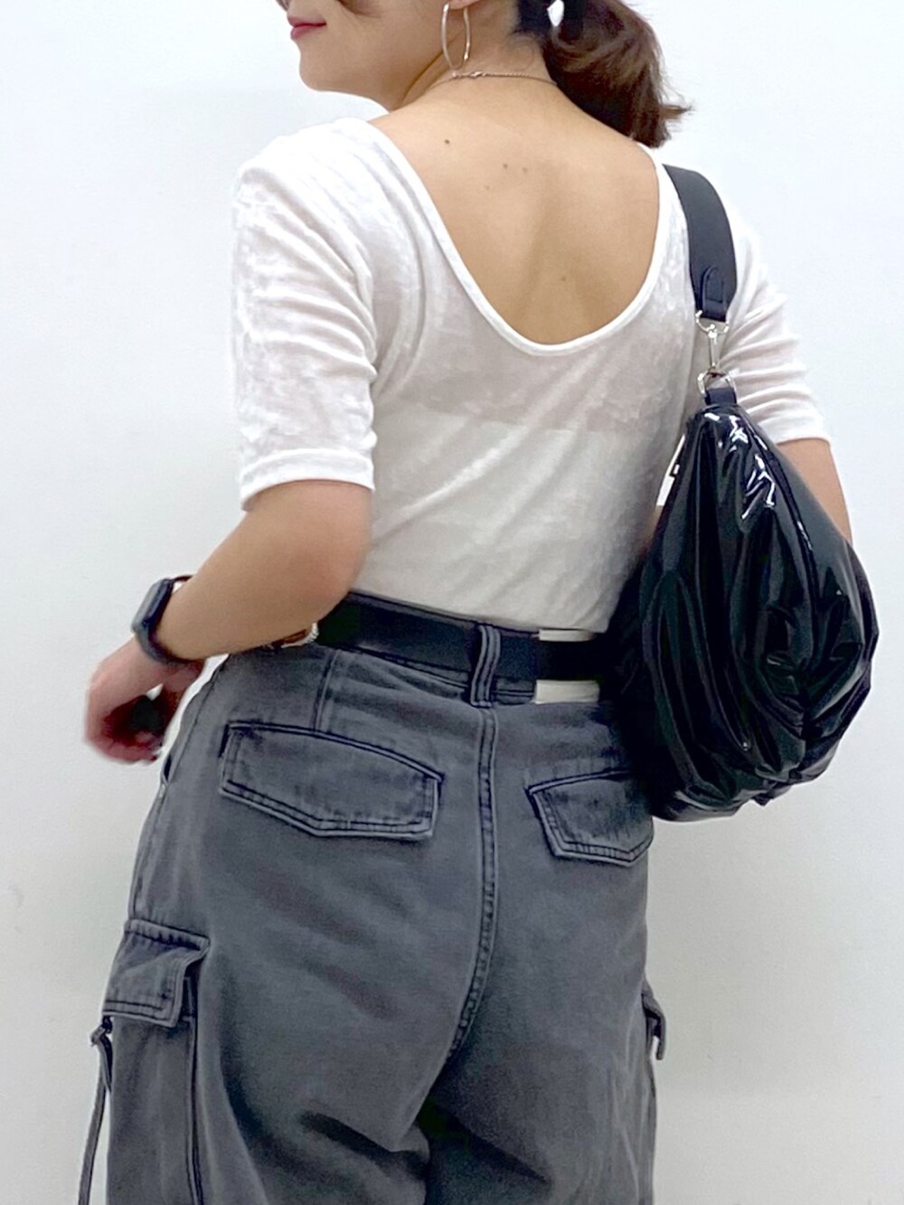 ブラック系のデニムパンツ、ホワイト系のスニーカー、ブラック系のショルダーバッグを着用したレディースの夏コーディネートの2枚目の写真