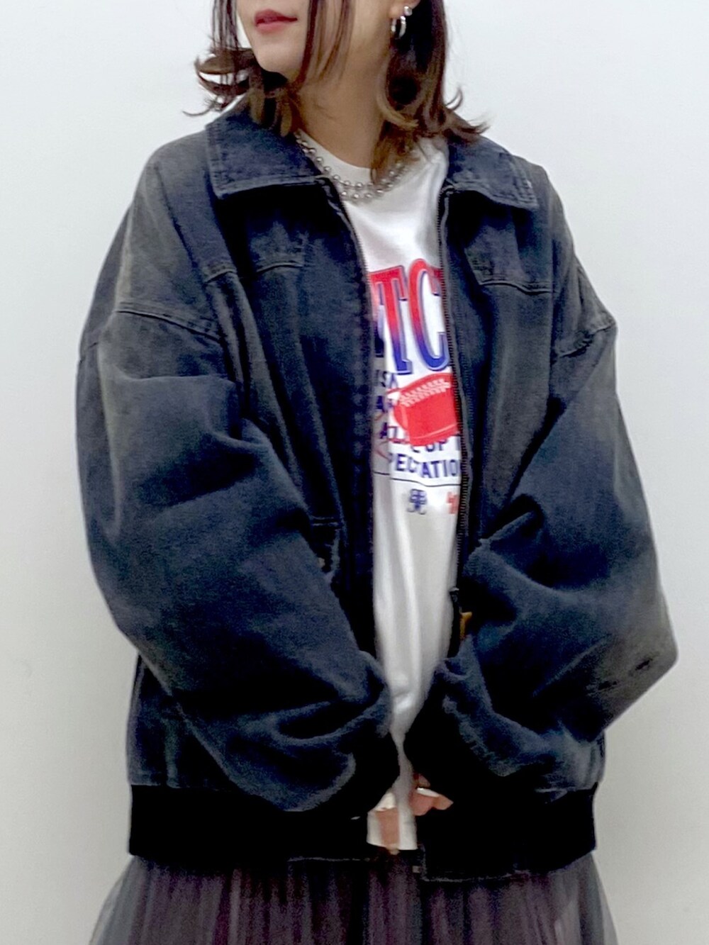ホワイト系のTシャツ/カットソー、ブラック系のデニムジャケット、グレー系のスカートを着用したレディースの冬コーディネートの2枚目の写真