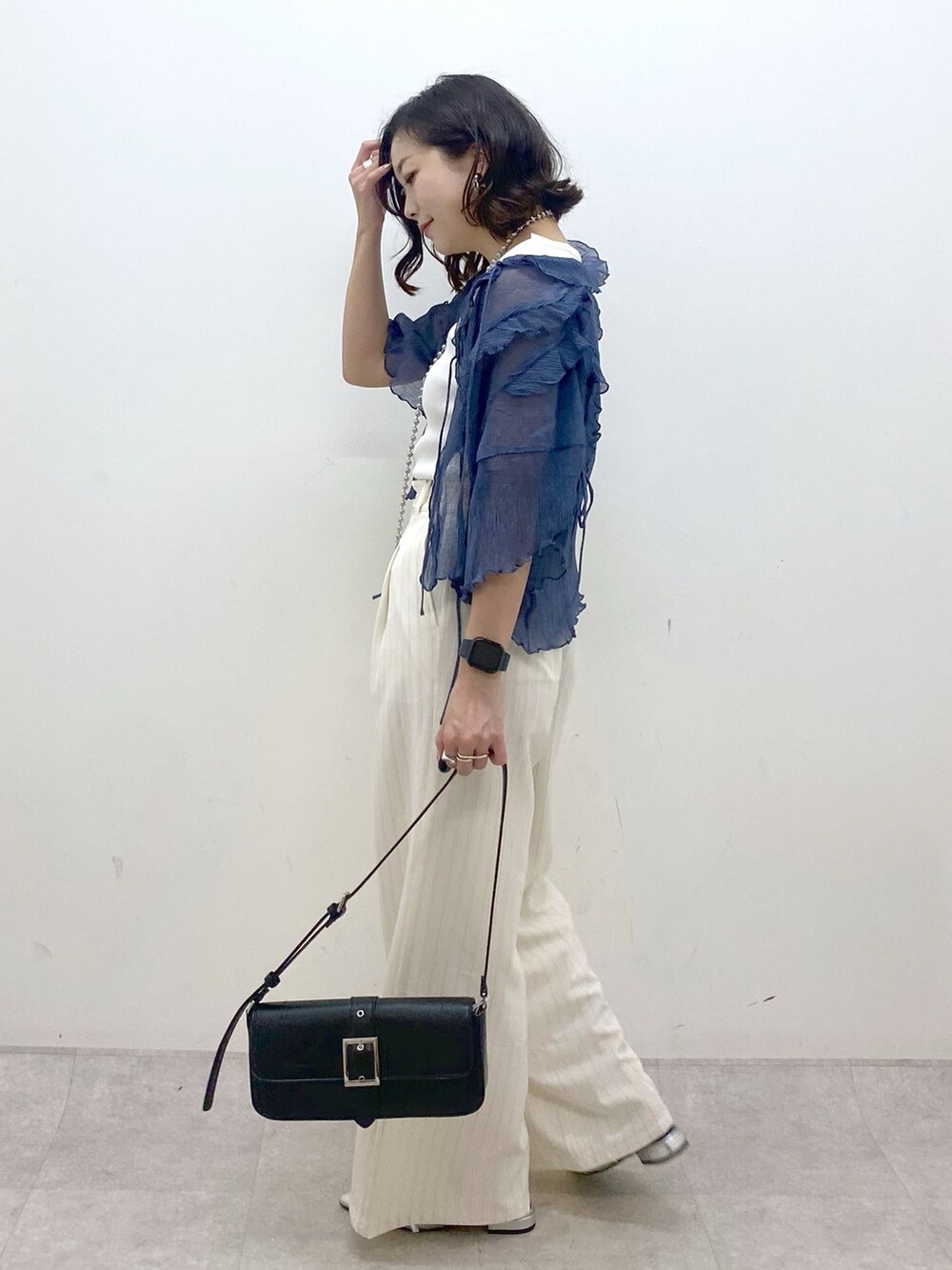 ホワイト系のスラックス、ブラック系のハンドバッグ、シルバー系のパンプスを着用したレディースの夏コーディネートの5枚目の写真
