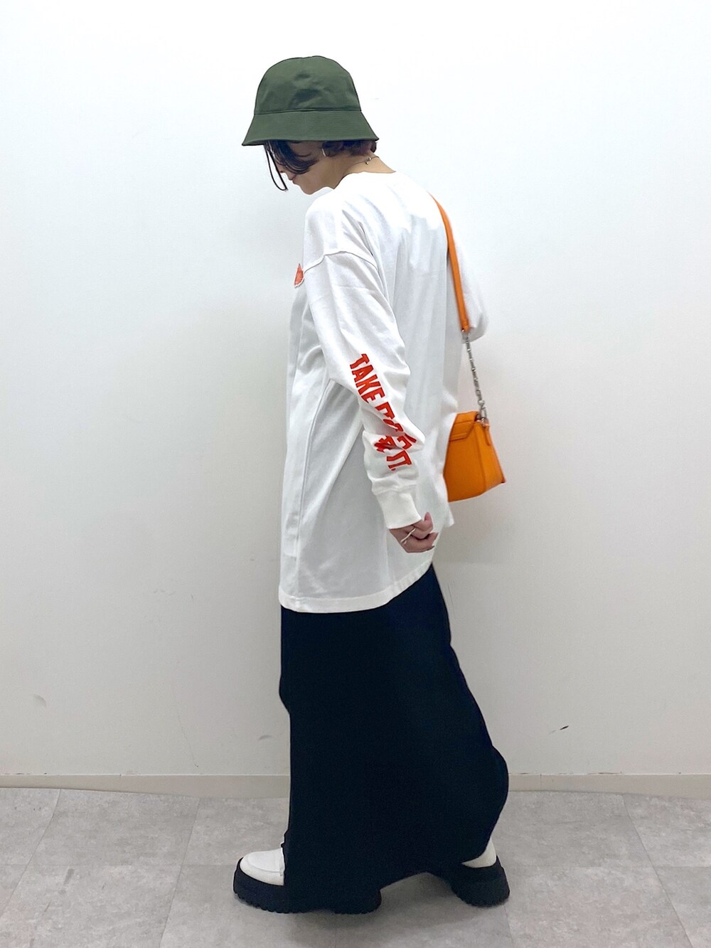 ブラック系のスカート、ホワイト系のブーツ、オレンジ系のショルダーバッグを着用したレディースの秋コーディネートの3枚目の写真