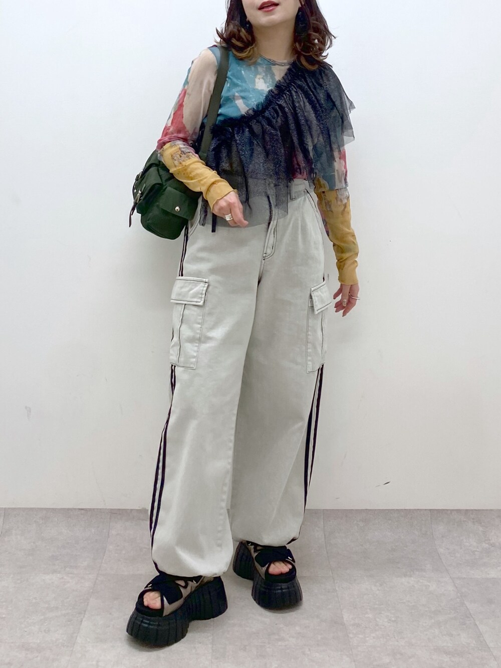 グリーン系のショルダーバッグ、その他のスニーカー、ホワイト系のデニムパンツを着用したレディースの春コーディネートの3枚目の写真