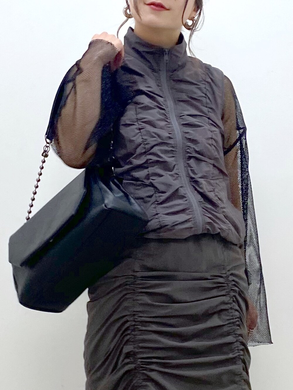 グレー系のスカート、ブラック系のショルダーバッグ、ブラック系のTシャツ/カットソーを着用したレディースの春コーディネートの2枚目の写真