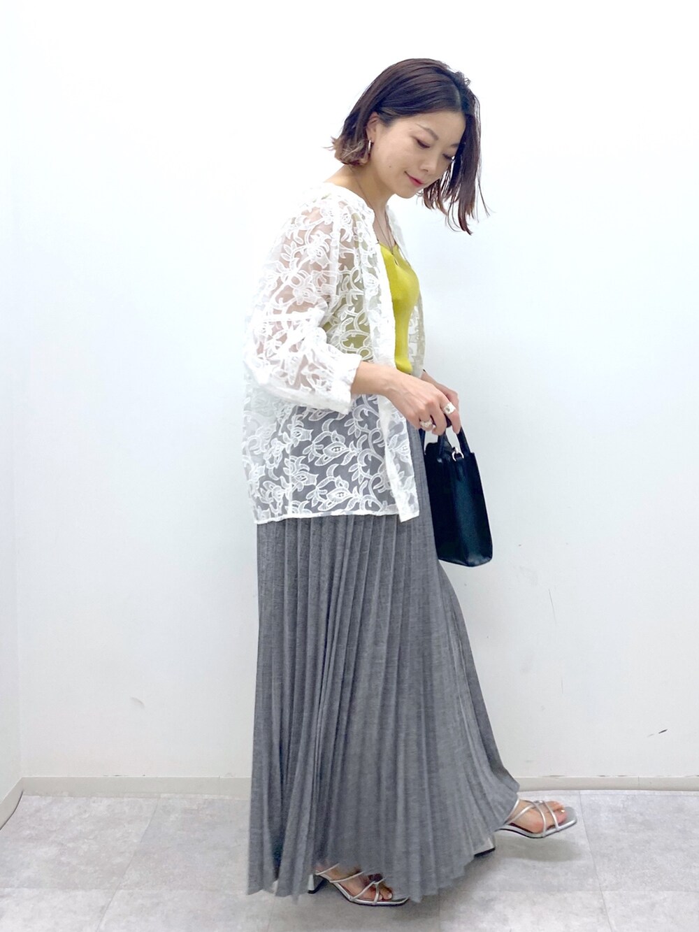 グレー系のスカート、イエロー系のタンクトップ、ホワイト系のトップスを着用したレディースの夏コーディネートの2枚目の写真