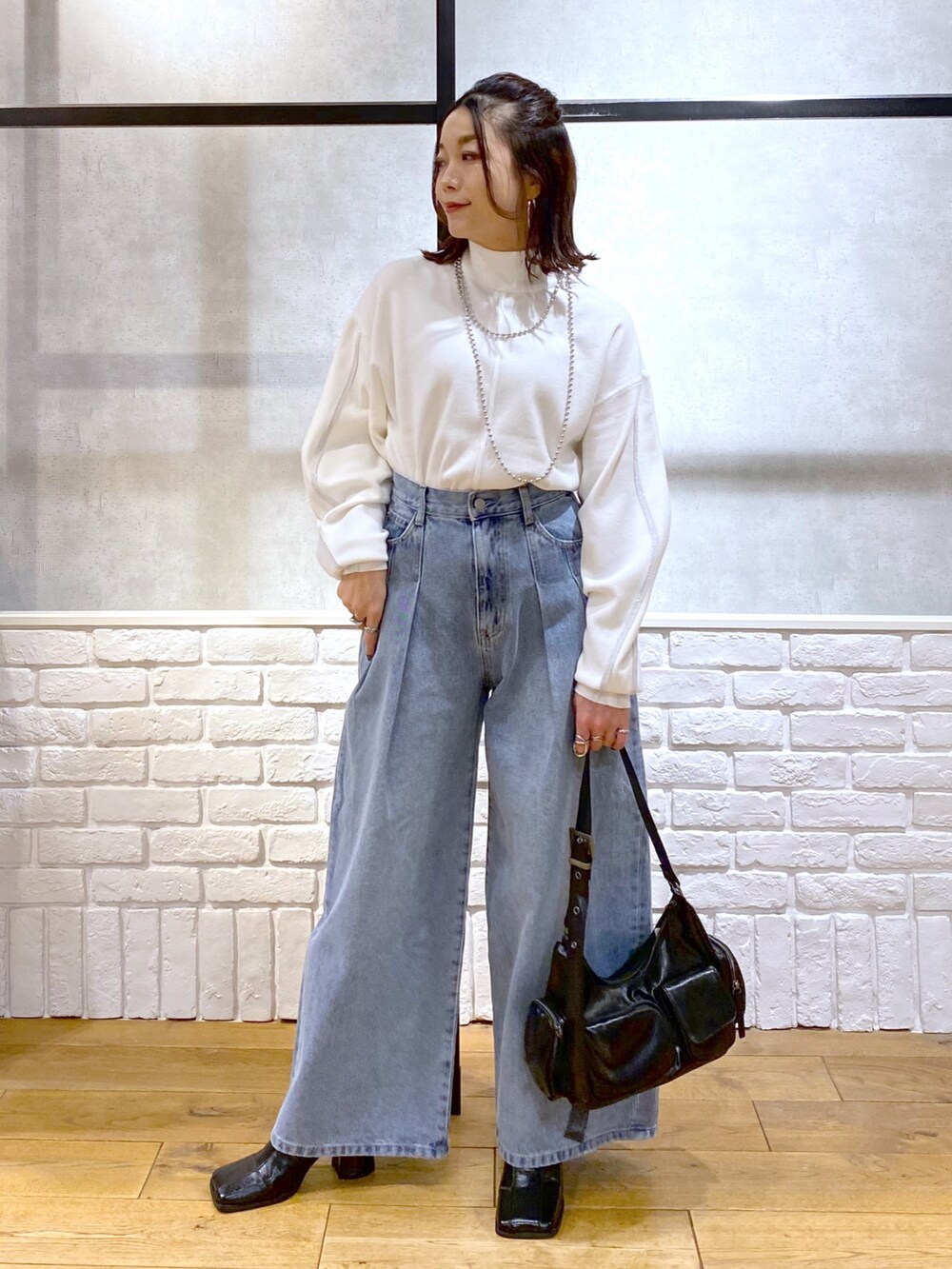 ホワイト系のニット/セーター、ブルー系のデニムパンツ、ブラック系のショルダーバッグを着用したレディースの冬コーディネートの4枚目の写真