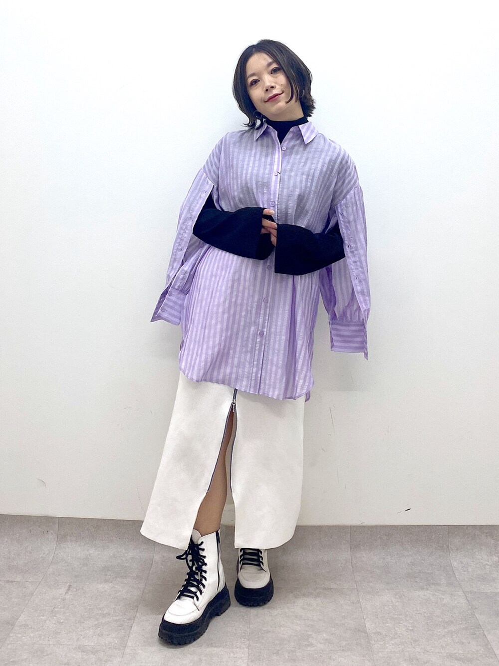 パープル系のトップス、ホワイト系のスカート、ホワイト系のシューズを着用したレディースの春コーディネートの2枚目の写真