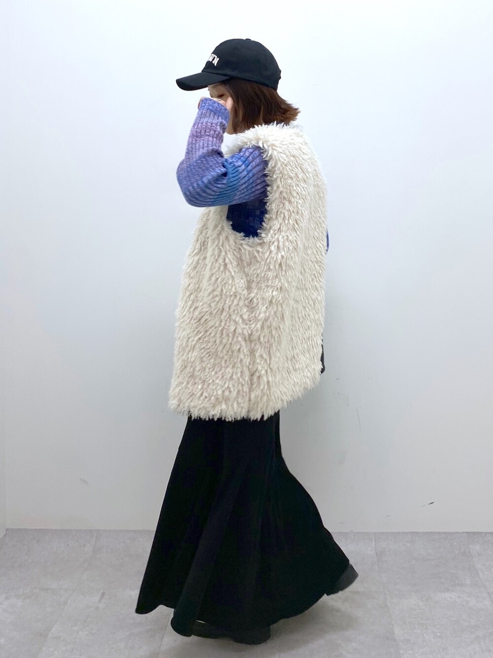 ブラック系のスカート、ホワイト系のシューズ、ブルー系のトップスを着用したレディースの秋コーディネートの3枚目の写真