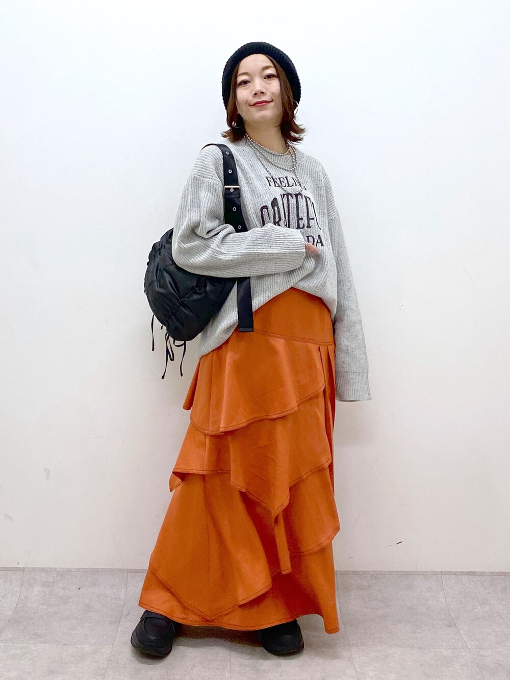 グレー系のニット/セーター、オレンジ系のスカート、ブラック系のローファーを着用したレディースの冬コーディネートの9枚目の写真