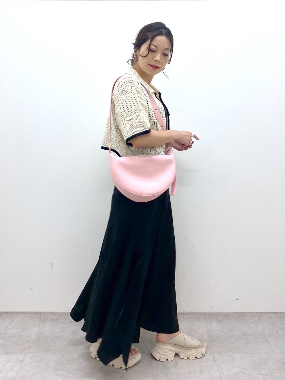 ブラック系のスカート、ホワイト系のカーディガン/ボレロ、ピンク系のショルダーバッグを着用したレディースの夏コーディネートの2枚目の写真