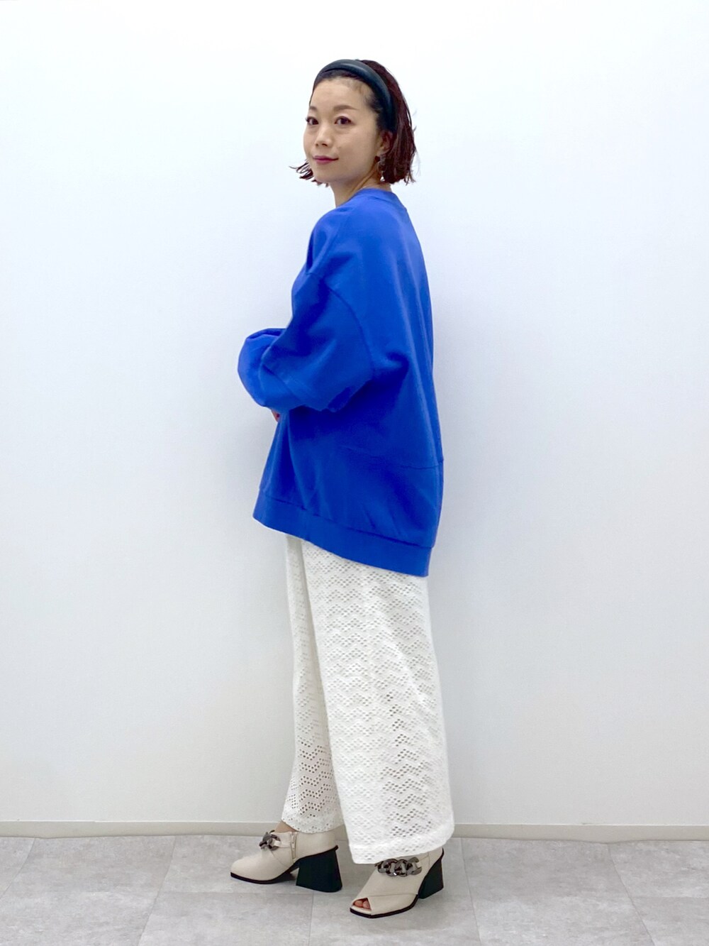 ブルー系のスウェット、ホワイト系のスカート、ホワイト系のパンプスを着用したレディースの冬コーディネートの3枚目の写真