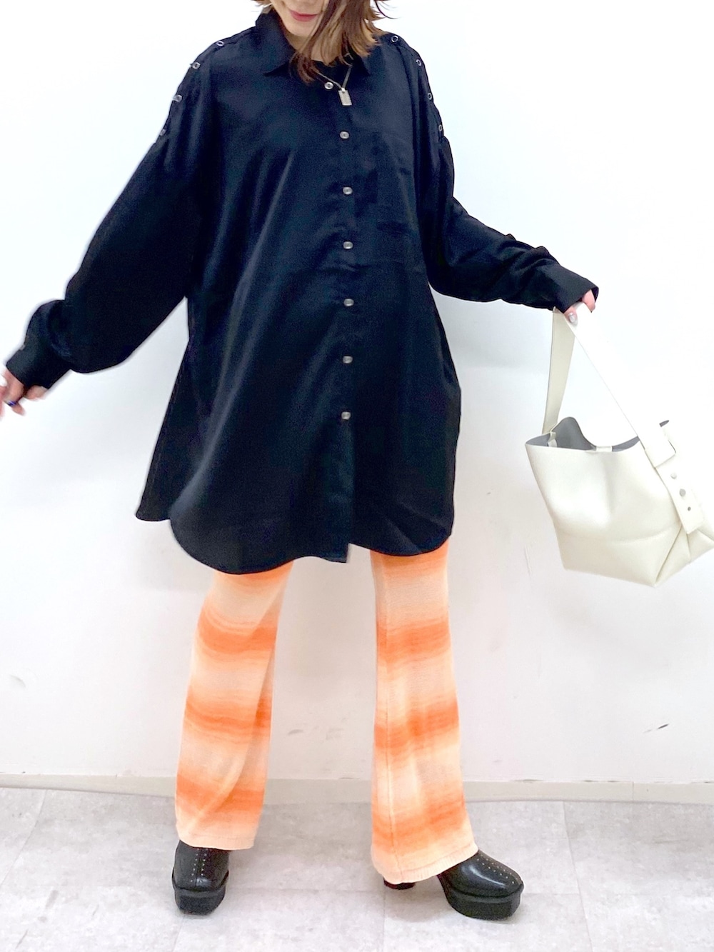 ブラック系のトップス、オレンジ系のその他パンツ、ブラック系のブーツを着用したレディースの夏コーディネートの5枚目の写真