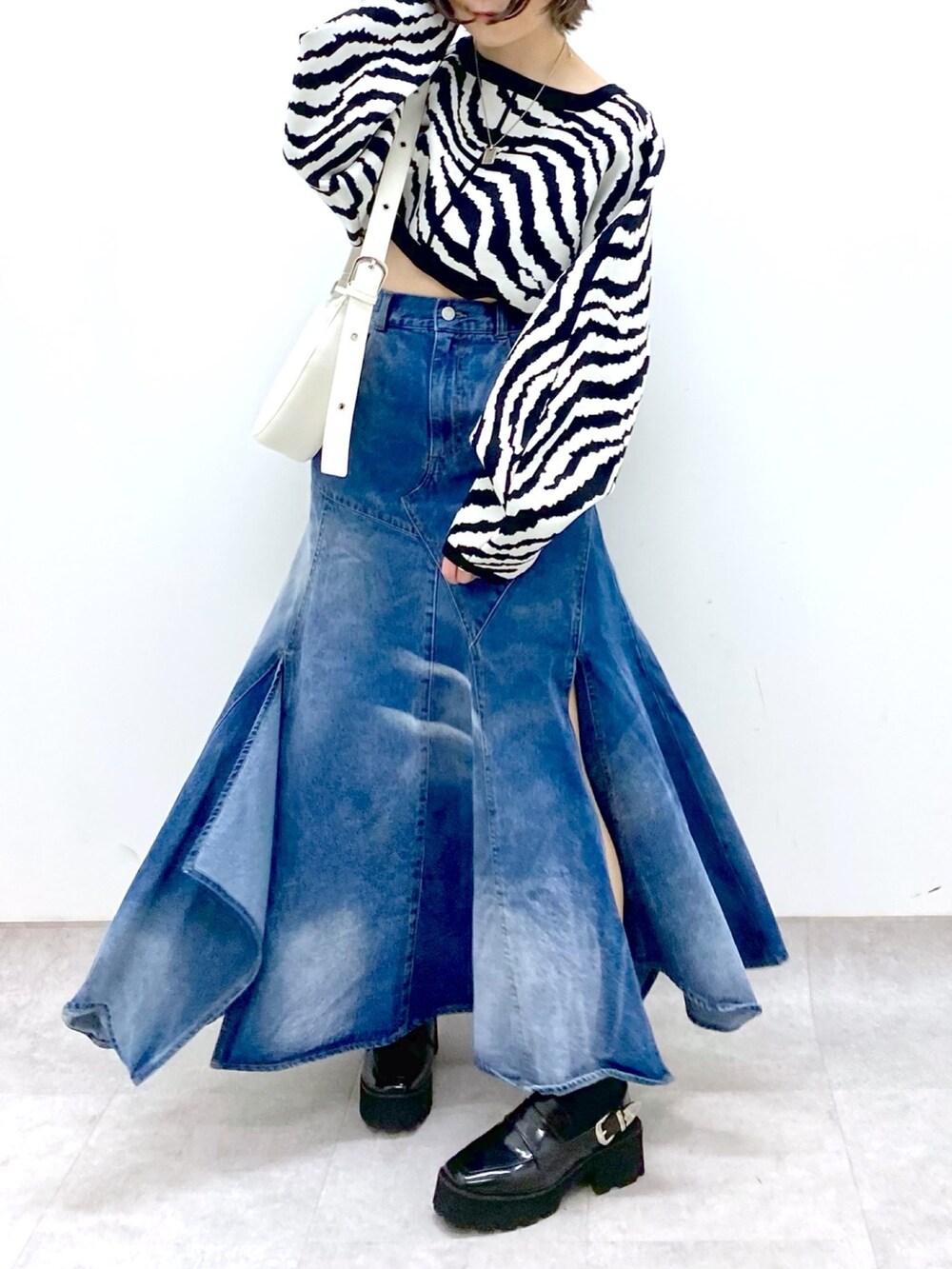 ブルー系のスカート、ブラック系のトップス、ホワイト系のショルダーバッグを着用したレディースの冬コーディネートの5枚目の写真