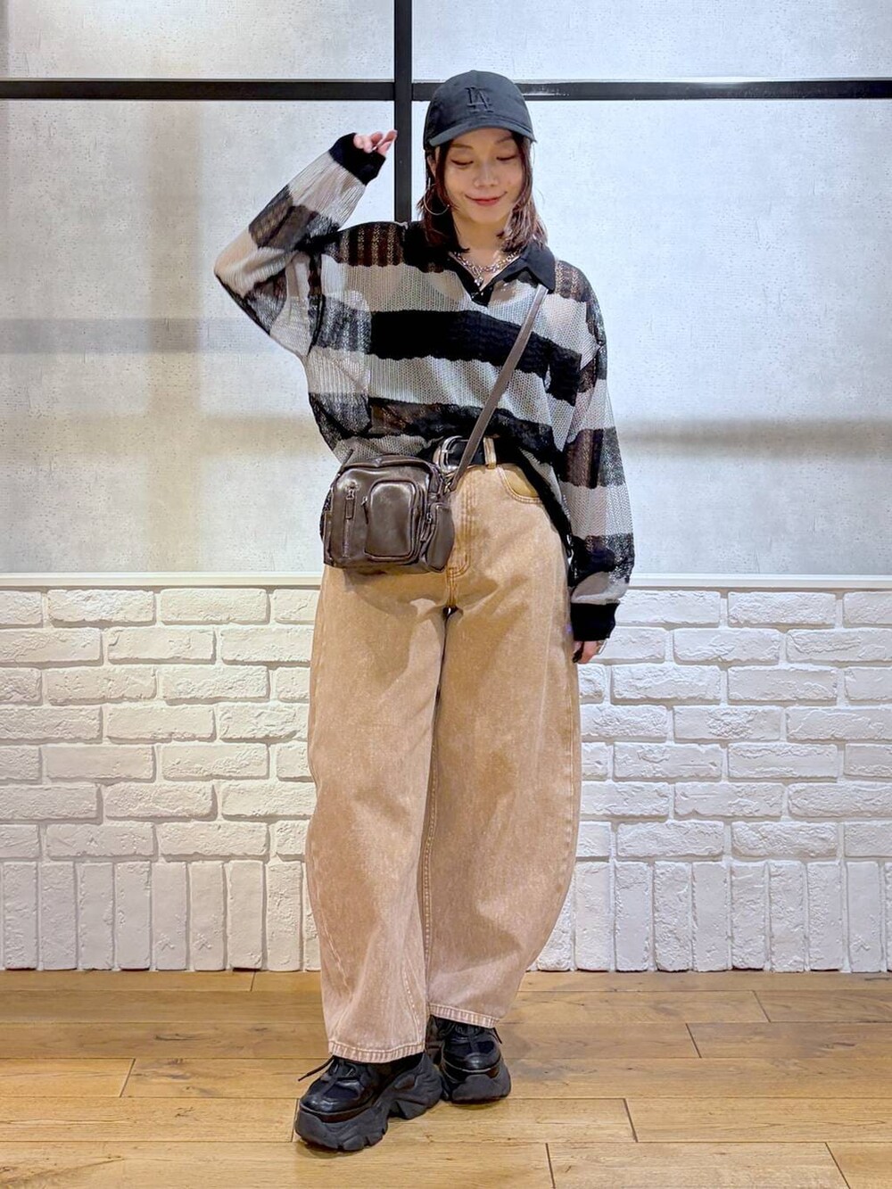 ブラック系のスニーカー、ブラウン系のデニムパンツ、ブラウン系のショルダーバッグを着用したレディースの春コーディネートの9枚目の写真