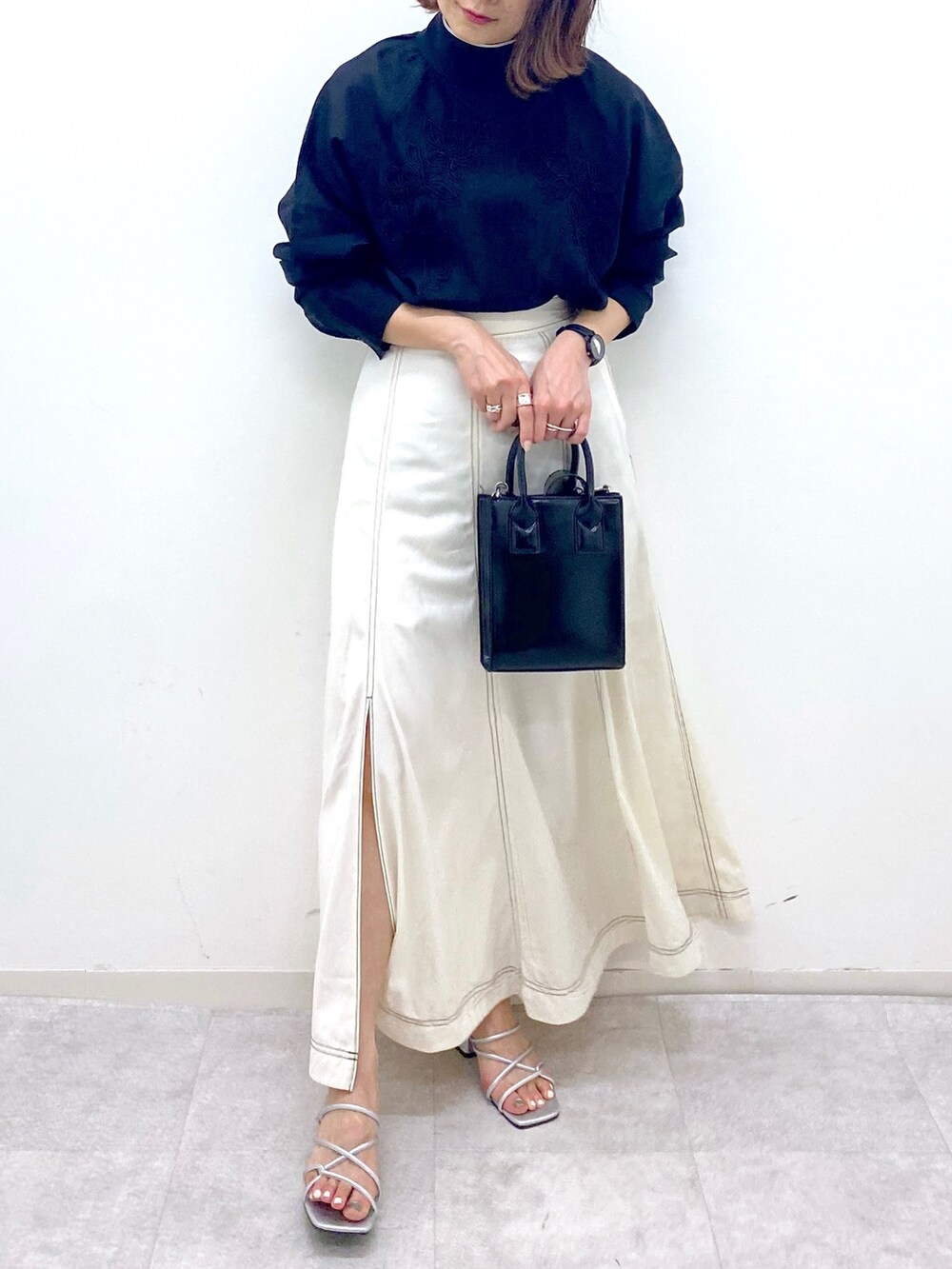 ホワイト系のスカート、シルバー系のサンダル、ブラック系のショルダーバッグを着用したレディースの夏コーディネートの5枚目の写真
