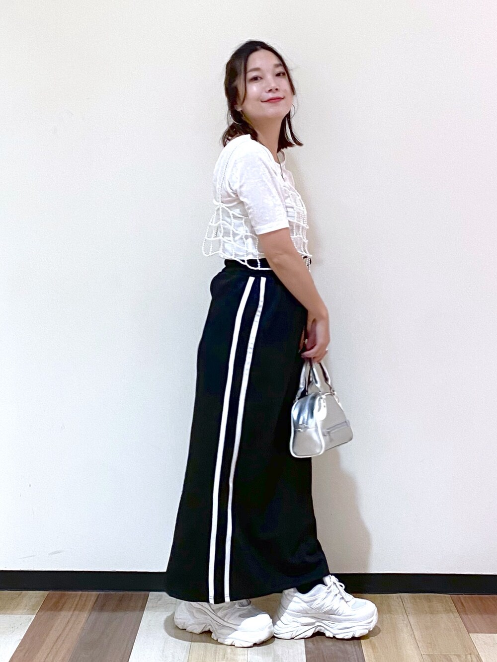 ブラック系のスカート、シルバー系のショルダーバッグ、ホワイト系のスニーカーを着用したレディースの夏コーディネートの6枚目の写真