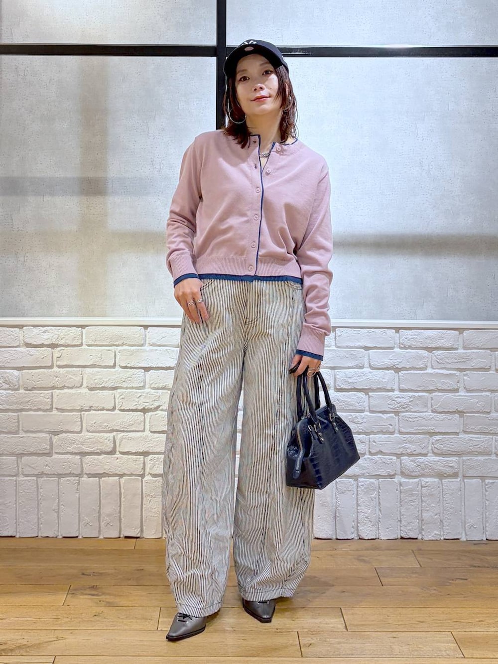 ブルー系のハンドバッグ、ブラウン系のサンダル、ブラック系のデニムパンツを着用したレディースの冬コーディネートの9枚目の写真