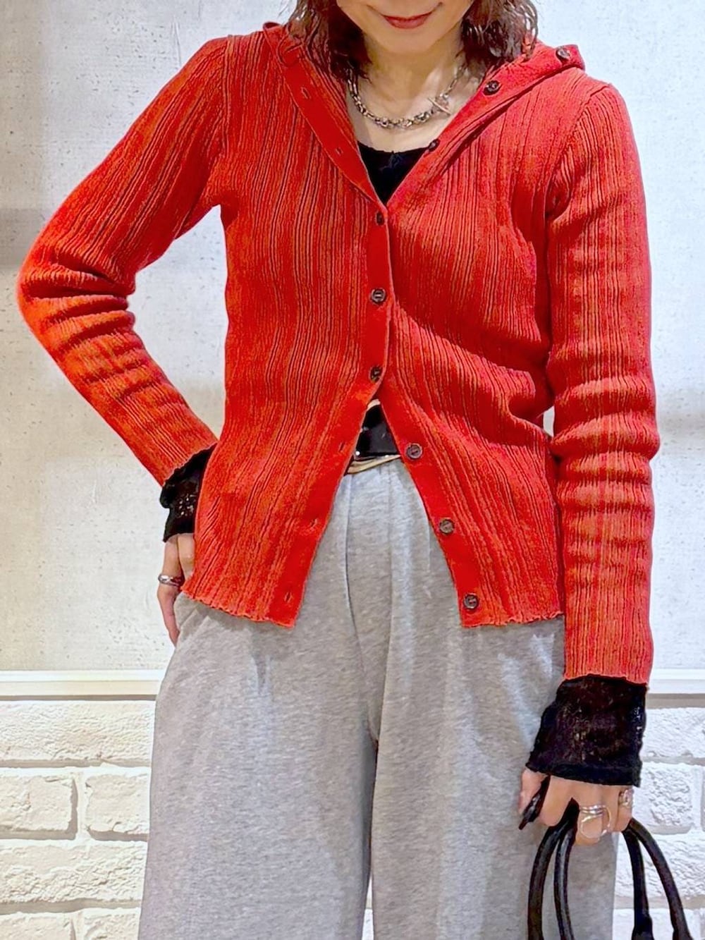 ブラック系のスニーカー、ブラック系のボストンバッグ、レッド系のカーディガン/ボレロを着用したレディースの春コーディネートの2枚目の写真