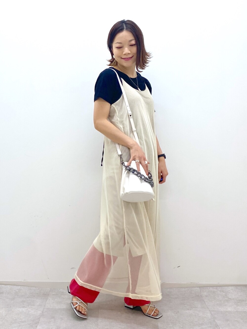 ブラック系のTシャツ/カットソー、ベージュ系のワンピース、ホワイト系のショルダーバッグを着用したレディースの夏コーディネートの2枚目の写真