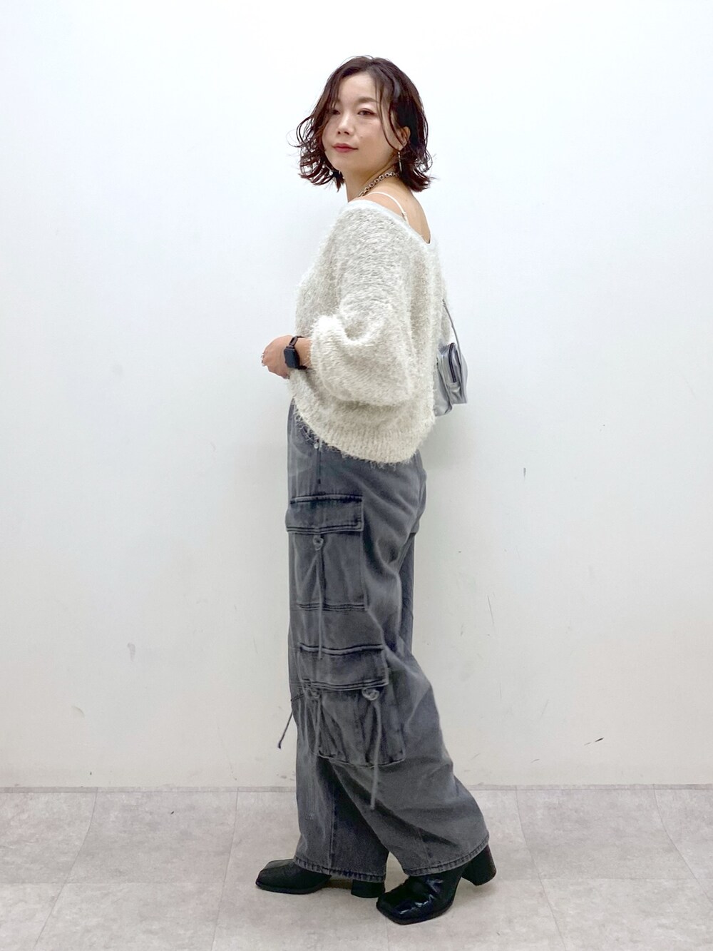 ブラック系のデニムパンツ、ブラック系のブーツ、シルバー系のショルダーバッグを着用したレディースの秋コーディネートの7枚目の写真