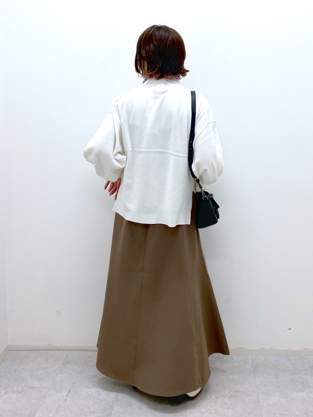 ホワイト系のブーツ、ブラウン系のスカート、ブラック系のバッグを着用したレディースの秋コーディネートの4枚目の写真