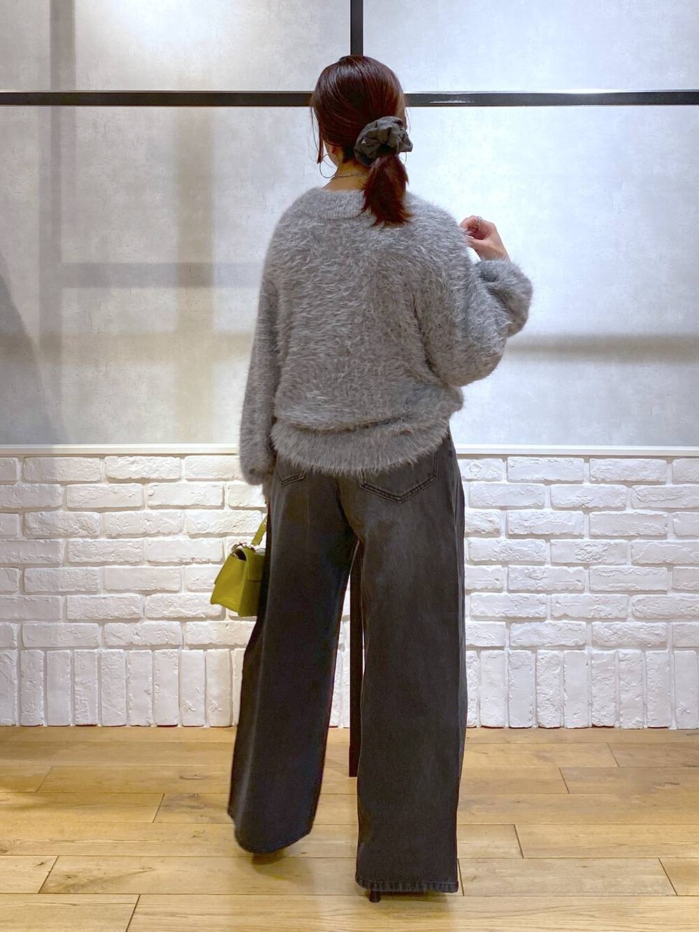 ブラック系のデニムパンツ、イエロー系のハンドバッグ、ブラック系のパンプスを着用したレディースの秋コーディネートの6枚目の写真