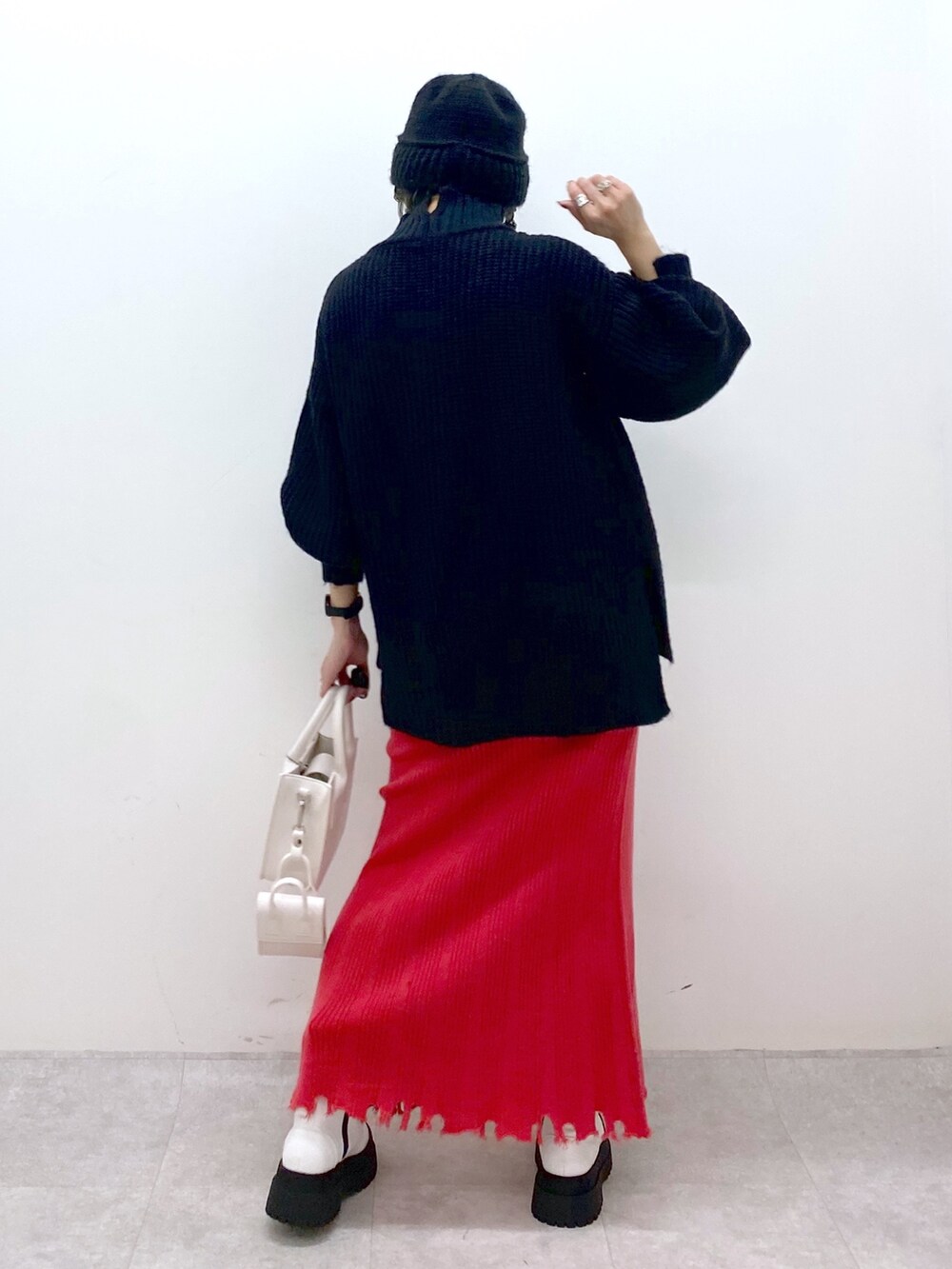 ブラック系のトップス、ゴールド系のスカート、ホワイト系のバッグを着用したレディースの秋コーディネートの3枚目の写真