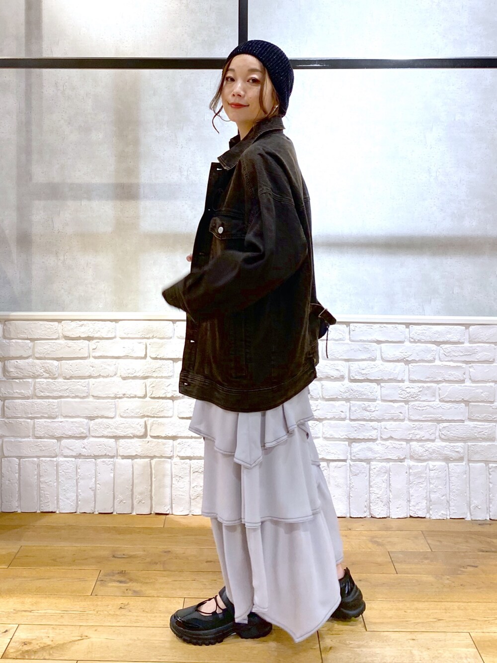 ブラック系のデニムジャケット、グレー系のスカート、ブラック系のスニーカーを着用したレディースの春コーディネートの5枚目の写真