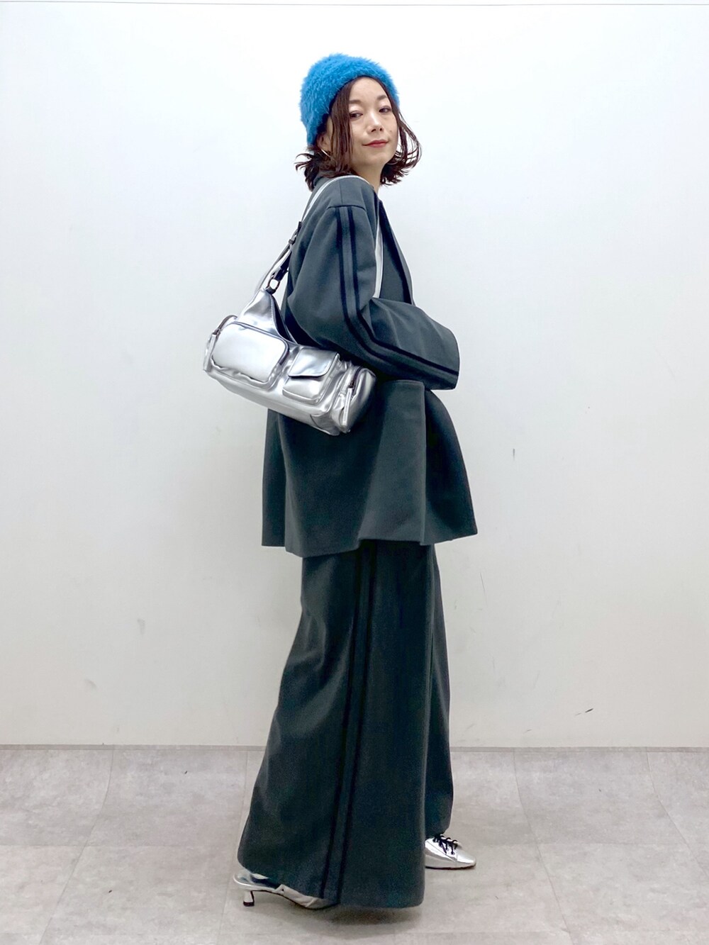 グレー系のスラックス、シルバー系のパンプス、シルバー系のショルダーバッグを着用したレディースの秋コーディネートの5枚目の写真
