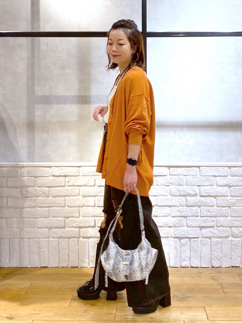 ホワイト系のタンクトップ、オレンジ系のカーディガン/ボレロ、ブラック系のデニムパンツを着用したレディースの春コーディネートの5枚目の写真