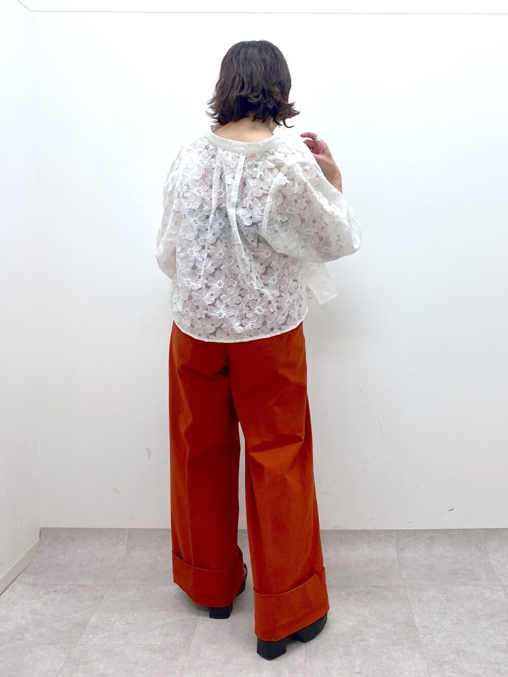 オレンジ系のスラックス、ブラック系のトップス、ホワイト系のシャツ/ブラウスを着用したレディースの春コーディネートの3枚目の写真
