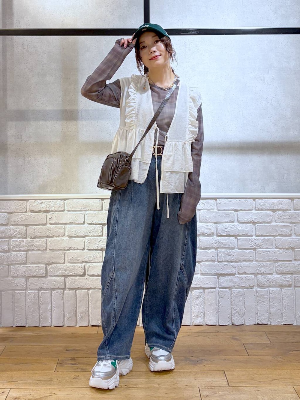 ホワイト系のスニーカー、ブラウン系のショルダーバッグ、ブルー系のデニムパンツを着用したレディースの春コーディネートの9枚目の写真
