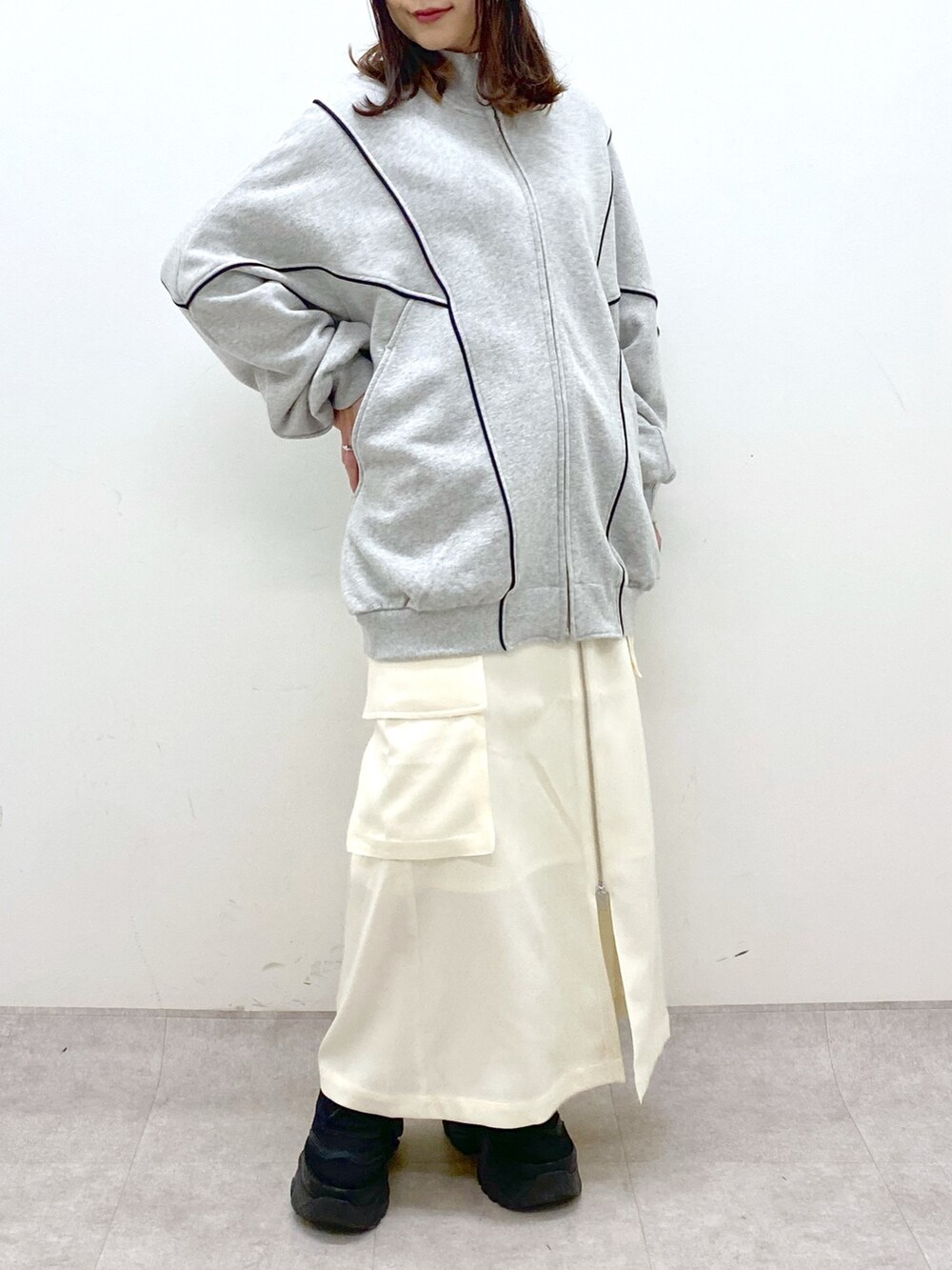 ホワイト系のスカート、ブラック系のスニーカー、グレー系のスウェットを着用したレディースの冬コーディネートの7枚目の写真